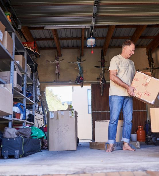 Clearing out some things. Shot of a man carrying a box in a garage Clearing out some things. Shot of a man carrying a box in a garage